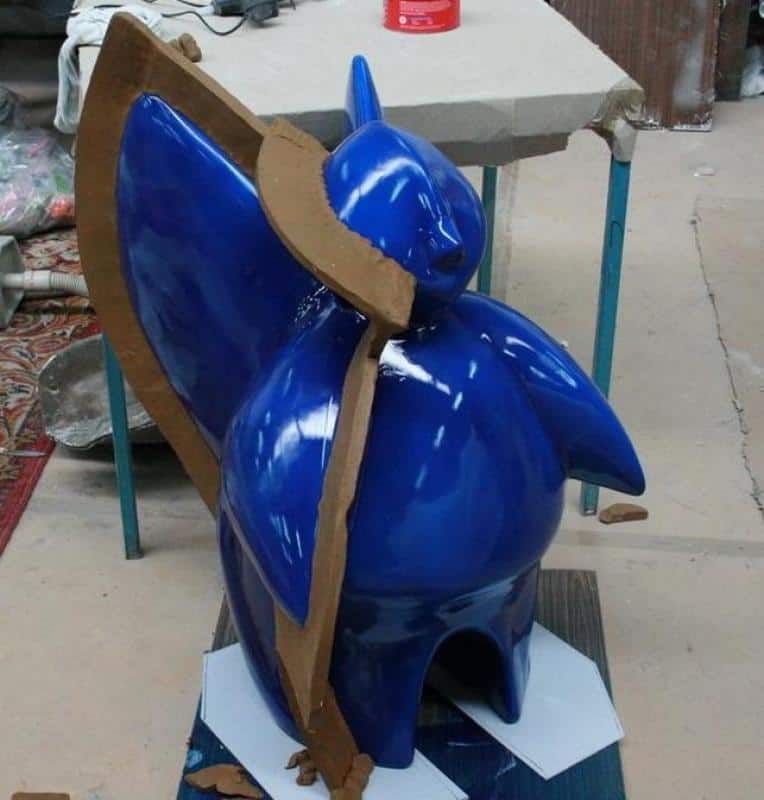 Futuristischer Engel für einen Messestand 4 Niebieska figurka w foremce z brązowego kartonu, umieszczona na stole roboczym.