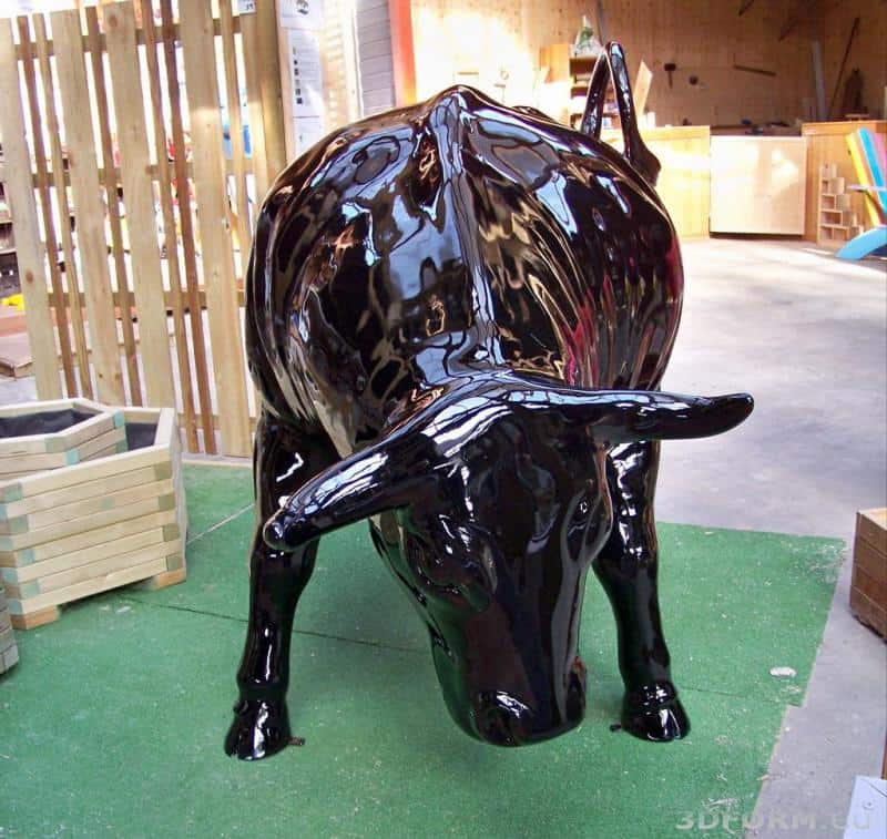 Große Event-Stierfigur 5 Czarna, błyszcząca rzeźba byka w pozycji pochylonej do przodu, umieszczona na zielonej sztucznej trawie w pomieszczeniu.