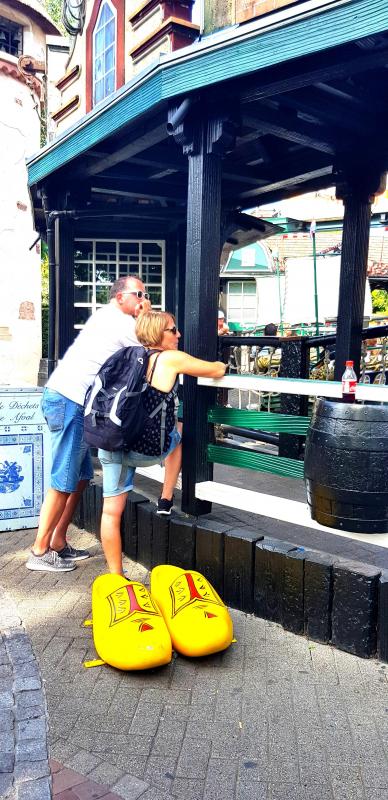 Große Holzschuhe 3 Para osób w żółtych, dużych drewnianych butach pozuje do zdjęcia przed budynkiem w stylu holenderskim.