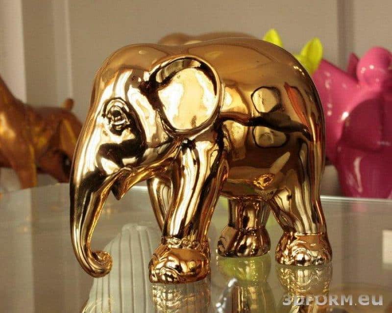 Metallisierte, verchromte Figuren 2 Figurka złotego słonia na szklanym stole.