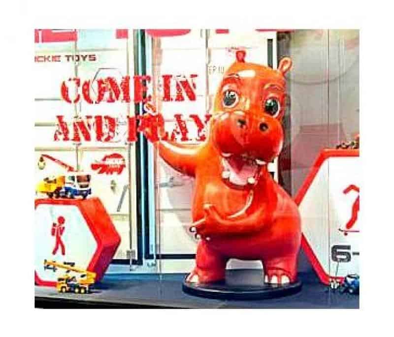 Werbe-Hippo 2 Czerwona figurka hipopotama w witrynie sklepowej z napisem