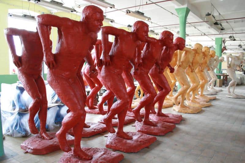 Werbung für die IAAF-Weltmeisterschaften 2 Figury męskich postaci w dziwnie wykręconej pozie, pomalowane na czerwono, pomarańczowo i biało, ustawione w rzędzie w przestrzeni magazynowej.