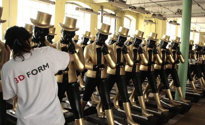 Große Johnnie Walker Figuren 4 Rzędy manekinów ubrane we złote garnitury i cylindry, osoba w białej koszulce z napisem