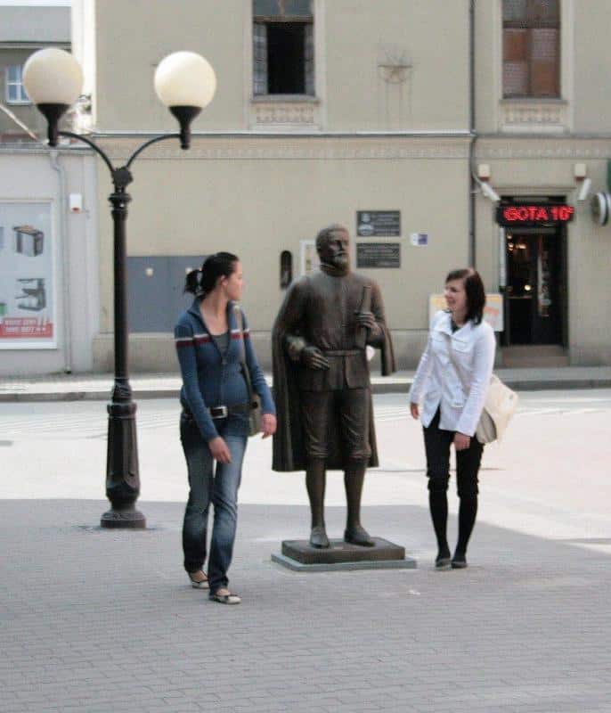 Denkmal - Kepler 4 Dwie kobiety obok rzeźby mężczyzny na chodniku w mieście.