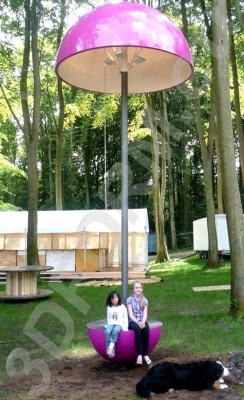 Festival-Lampen 2 Dwoje dzieci siedzących na różowej huśtawce w kształcie grzyba w lesie, obok leży czarny pies.