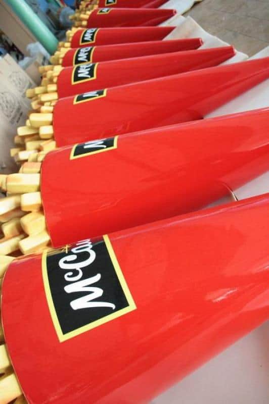 Czerwone pudełka na frytki z logo McCain ustawione w rzędzie na stole.