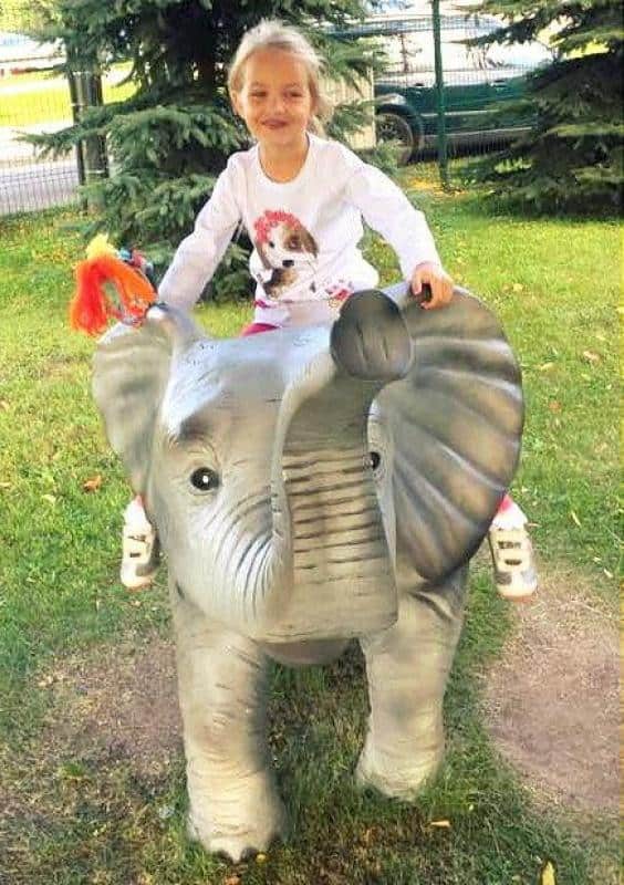 Figuren in einem Themenpark 5 Dziewczynka siedząca na figurce słonia na placu zabaw.