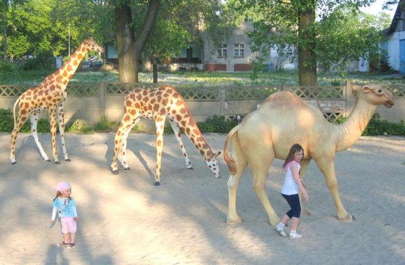 Figuren in einem Themenpark 4 Dzieci bawiące się obok figur żyraf i wielbłąda w parku.