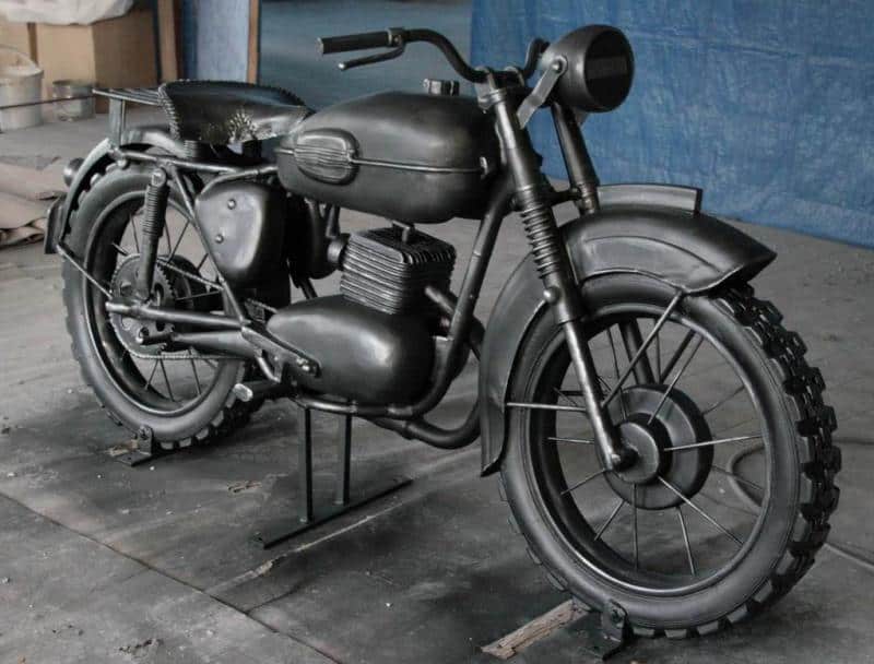 Ikonisches Motorrad - Denkmal in Żagań 1 Czarny, zabytkowy motocykl na tle niebieskiej ściany.