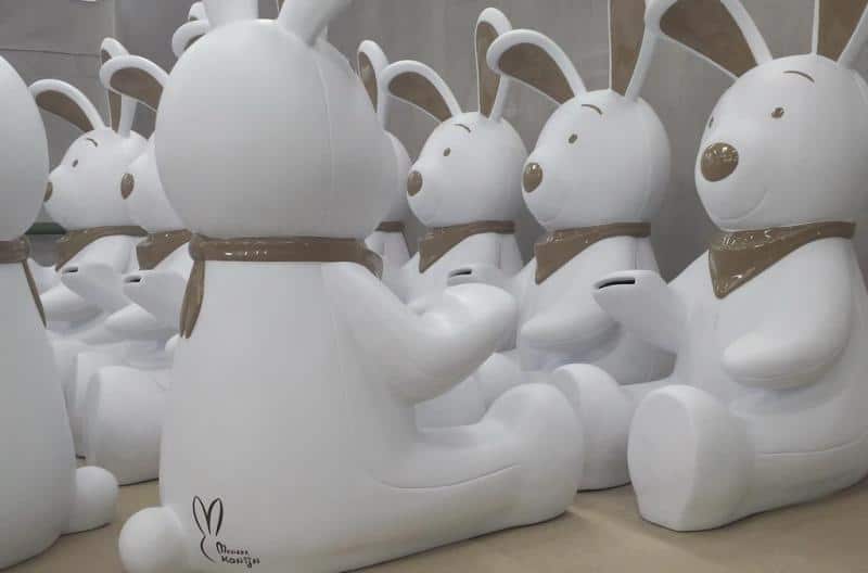 Białe figurki królików z brązowymi detalami siedzące w rzędach.