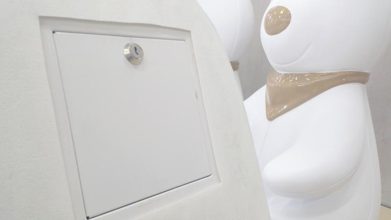 biała skrzynka zamykana na klucz na tle dużych, białych figur przypominających misie