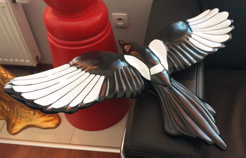 Schwarm von Elstern in Berlin 3 Czarna rzeźba ptaka z rozłożonymi skrzydłami leżąca na kanapie.