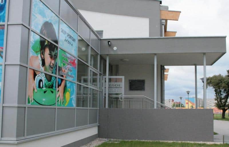 Dekoratives Informationsschild 3 Budynek z dużym plakatem przedstawiającym dziecko na dmuchanym materacu oraz wejściem z napisem